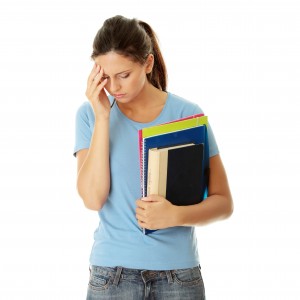 teen girl holding books with hand on head