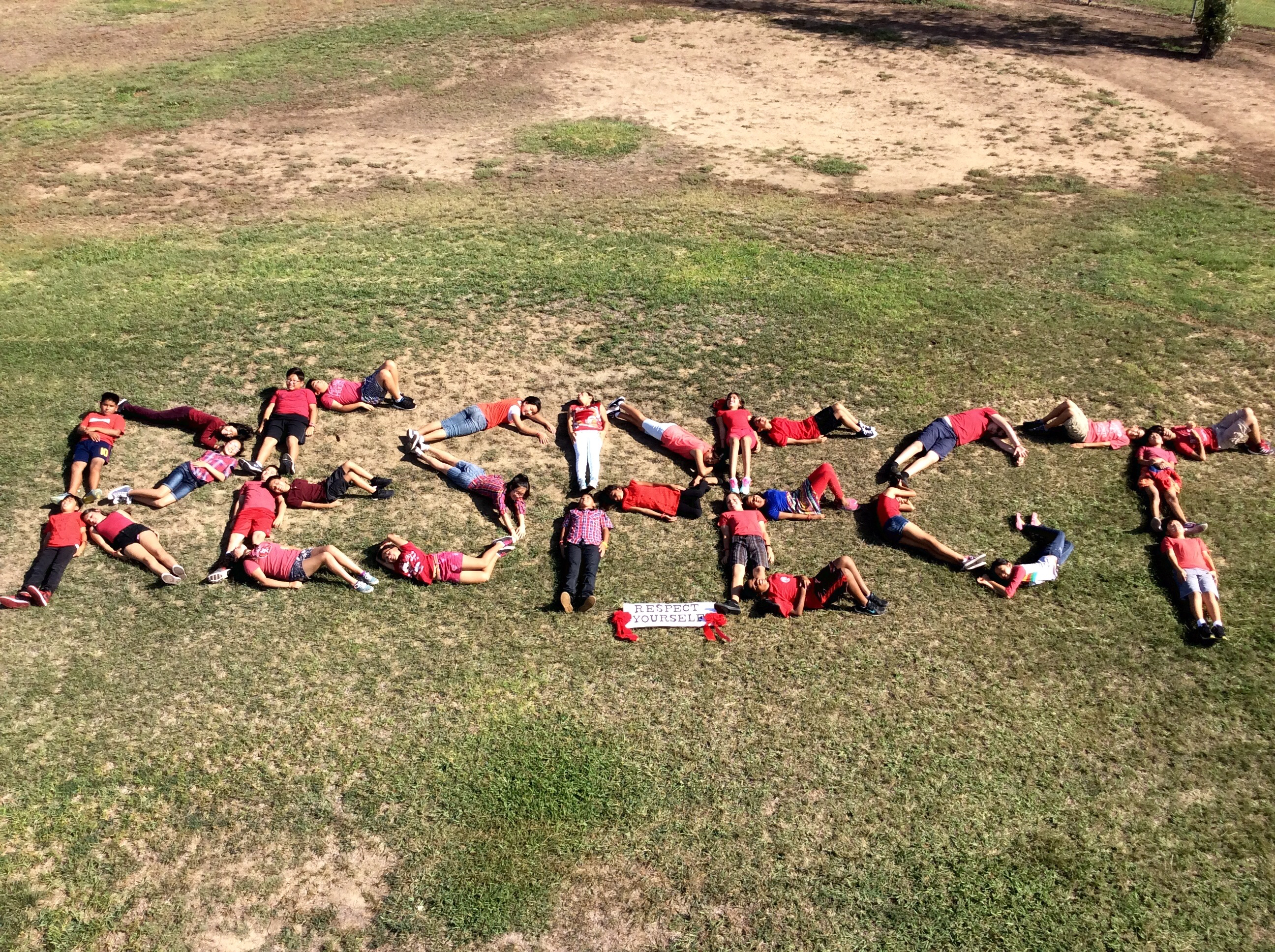 Students lying in a field, spelling out "RESPECT."