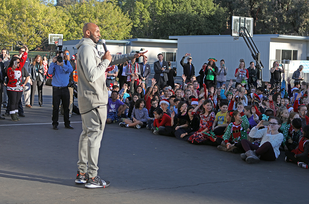 Kobe talks with students at an assembly.