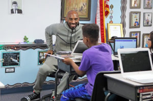 Kobe Bryant sits in chair chatting with student