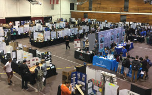 Booths inside Chapman University gym display students' ocMaker Challenge projects