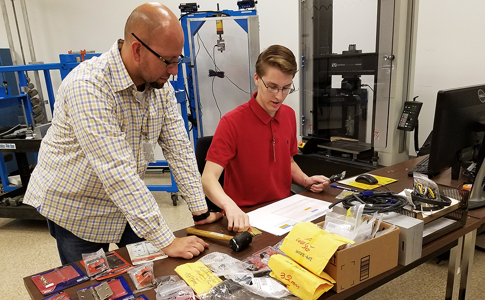 Laboratory technician Tony Figueroa helps El Toro High student Mason Maragon work design an experiment to test the integrity of a pad lock.