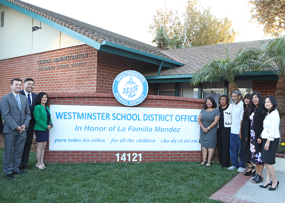 educators and activists stand in front of new dedication sign for school district