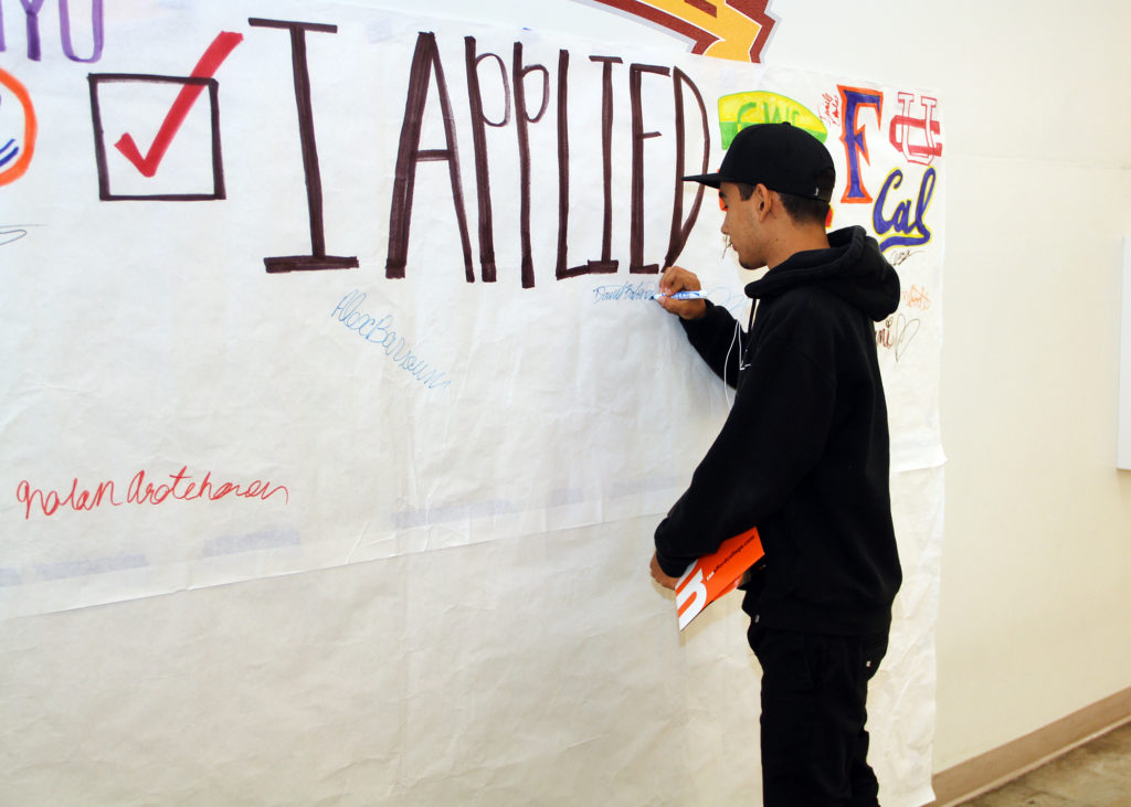 Student signing a banner that reads, "I applied."
