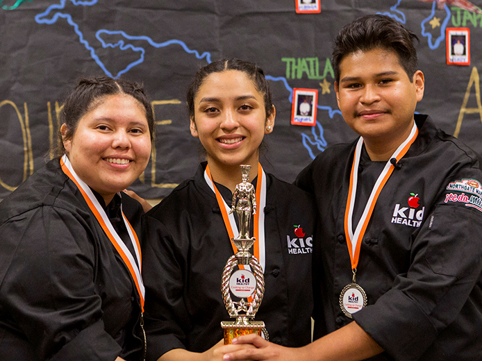 Three high school culinary students with trophy