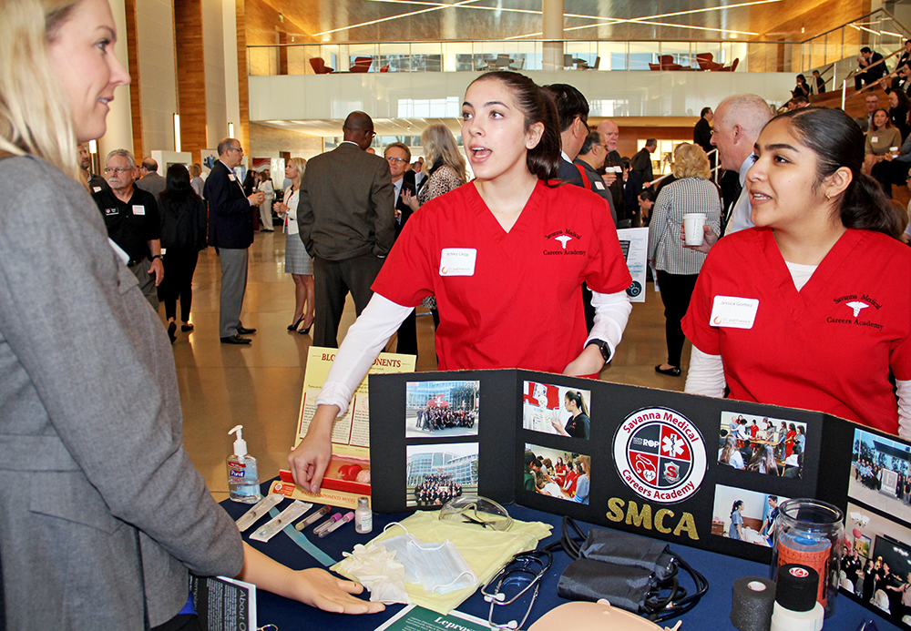 students show off their work to attendee at OC Pathways Showcase