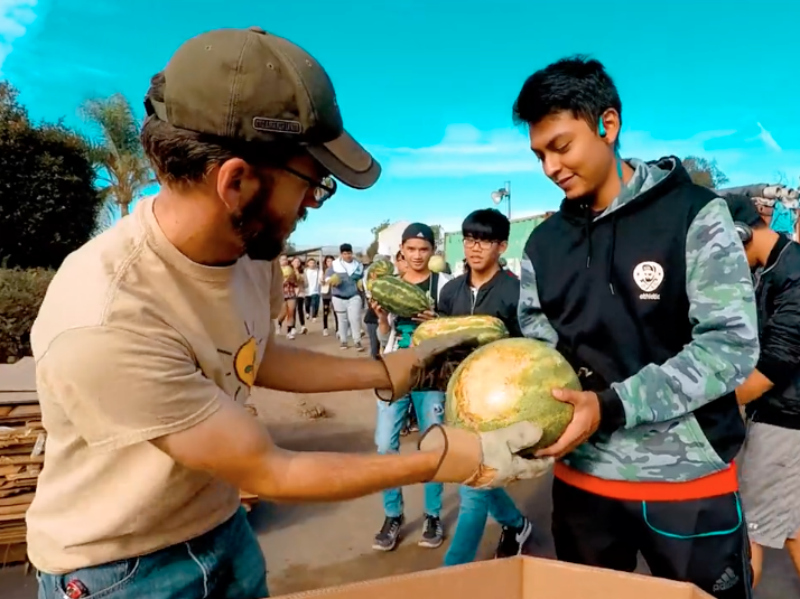 Student hands teacher a watermelon