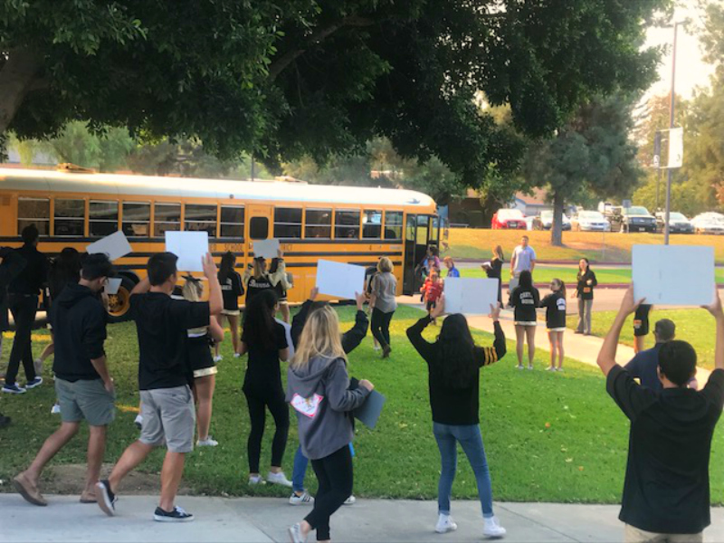 Cheerleaders, ASB leaders and others greet an arriving school bus