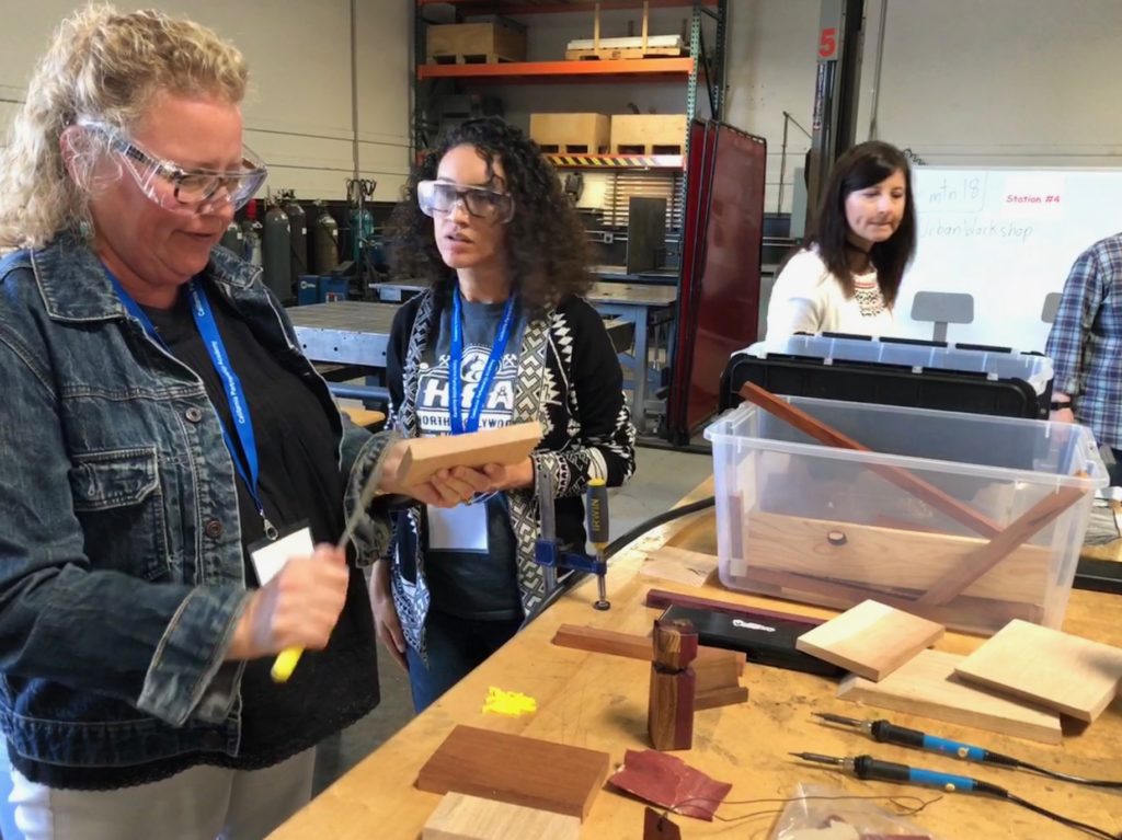 School counselor filing a block of wood with two educators in the background