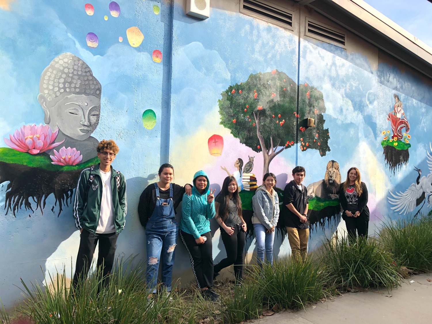 Students stand in front of a mural