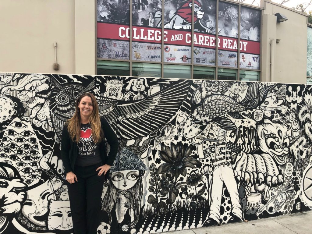 Teacher Daina Anderson in front of a mural