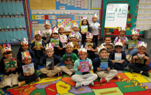 students in a classroom each hold up donated books
