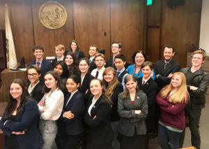 students from mock trial team pose for photo in courtroom