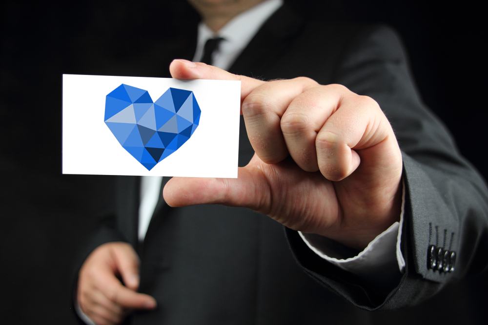 kindness heart, man in suit holding business card
