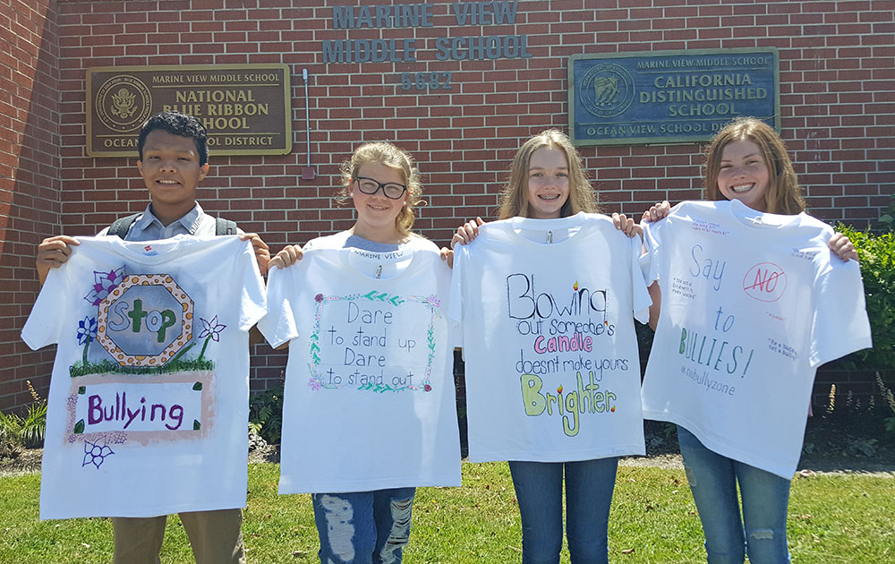 Students from Marine View hold up t-shirts with anti-bullying messages they created