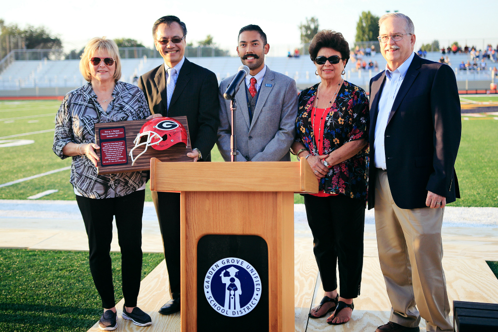 Sally Monsoor, Michael's mother, is presented with a mounted football helmet signed by Michael's former teammates at Garden Grove High School