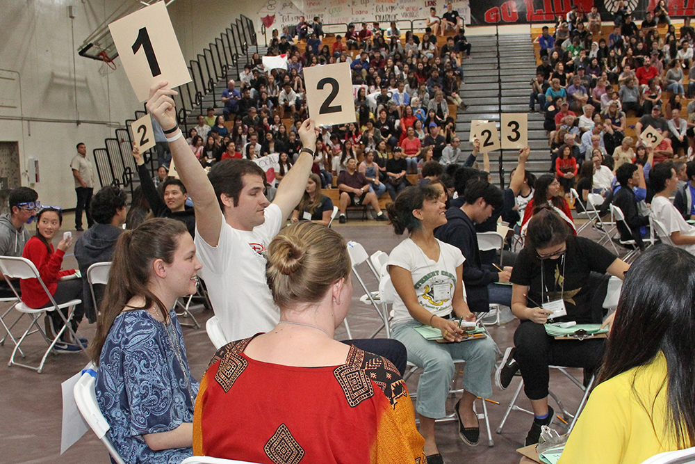 A student on an Academic decathlon team holds up two numbers indicating his team answered a question correctly