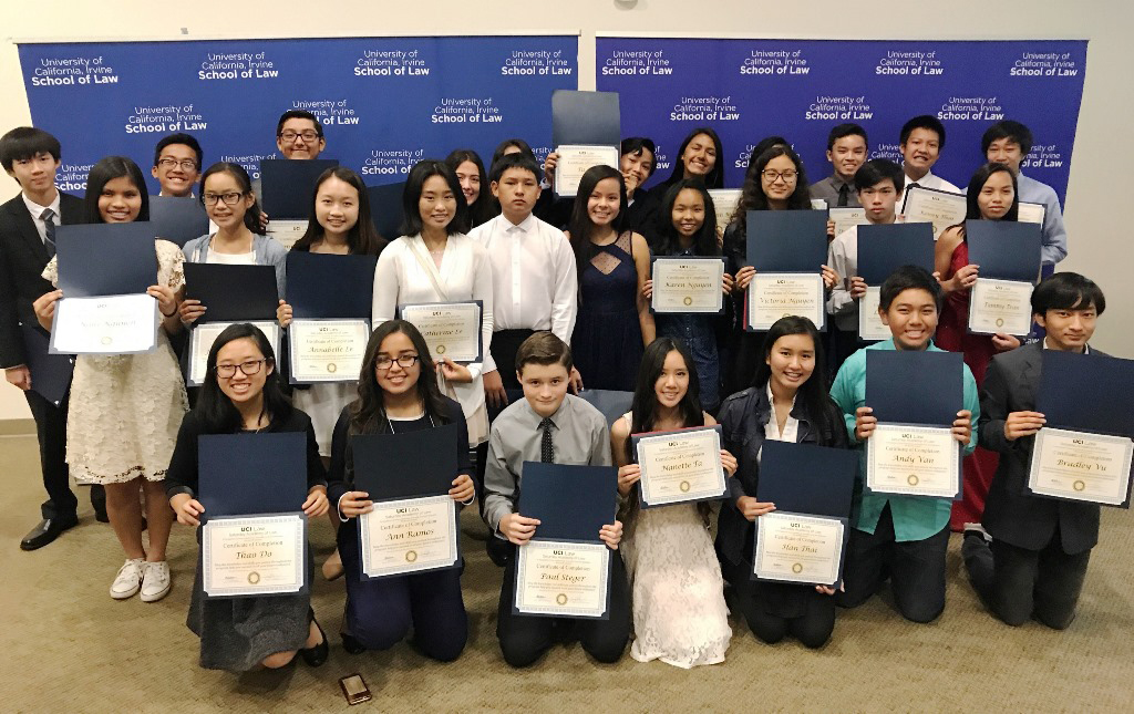 a roup of students hold up certificates they received from a law school program