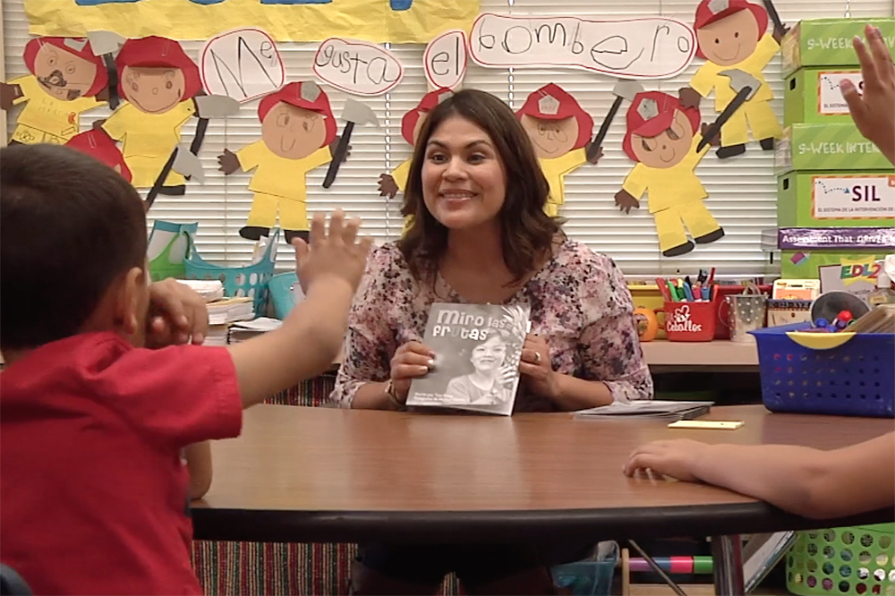 female teachers shows two students a book