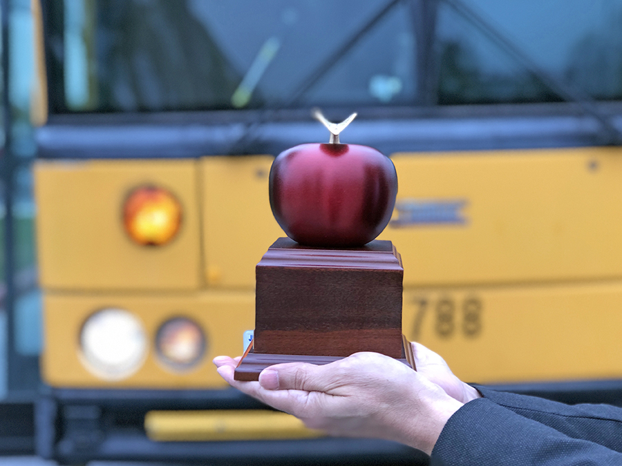 apple trophy in front of a bus
