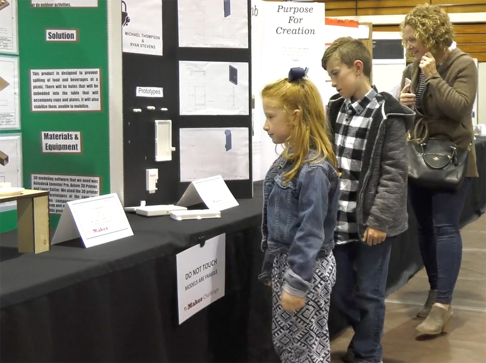 students and a parent view exhibits and science fair