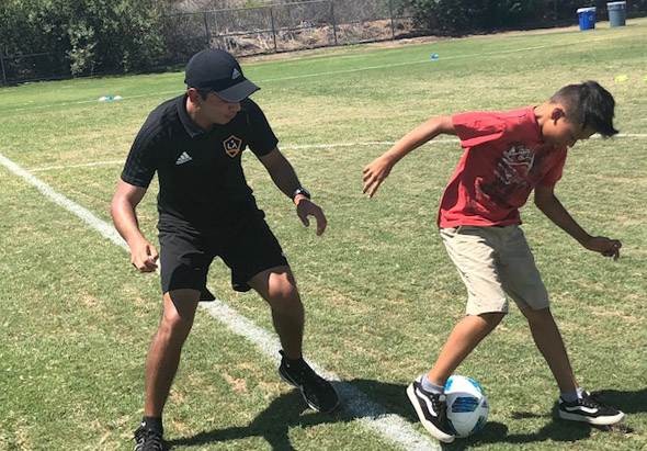 student and coach playing soccer