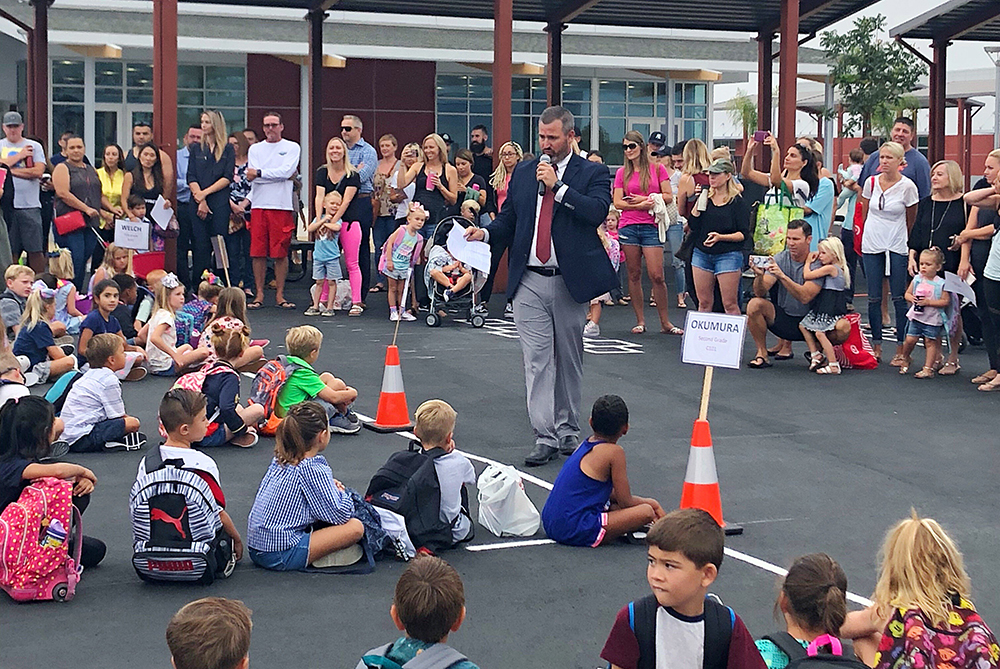 principal talks to students on the playground