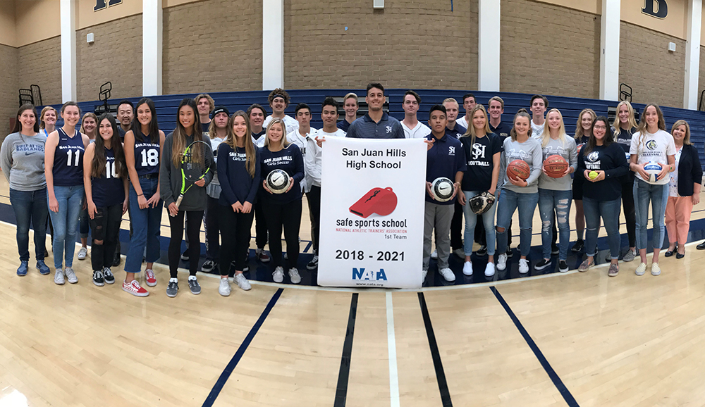 student athletes and staff from San Juan Hills High pose inside the school gym