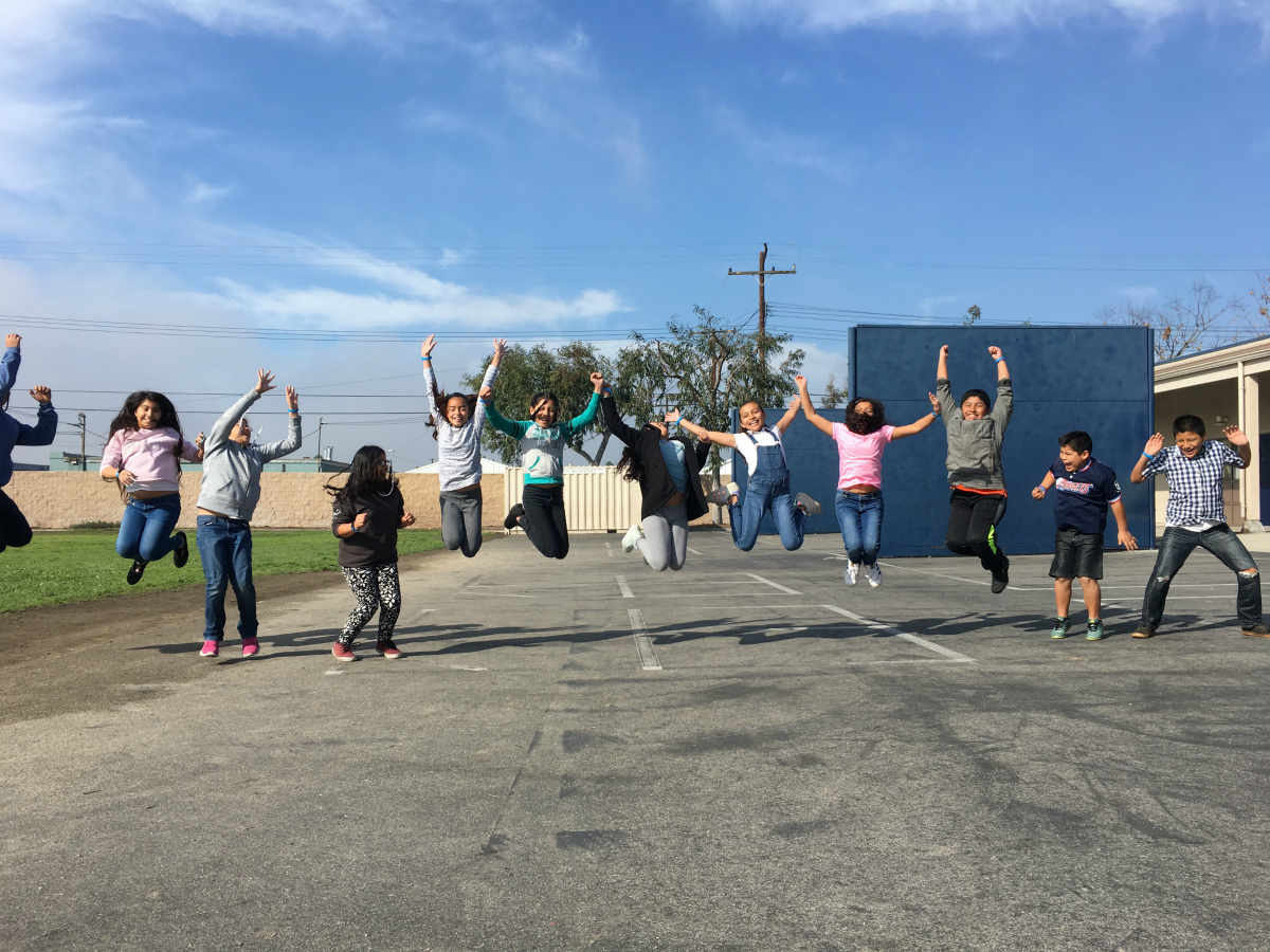 Elementary students on a playground jumping in the air