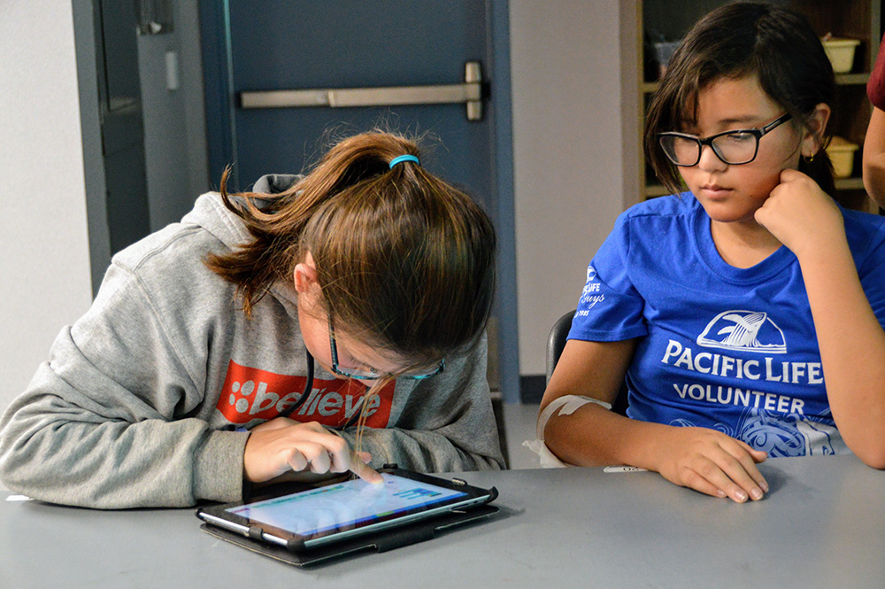 two girls work on an ipad coding project