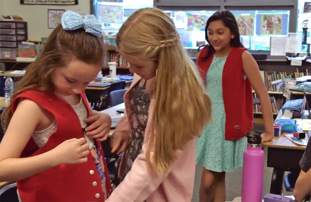 students in a classroom try on vests