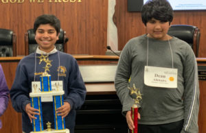 Two students hold up trophies