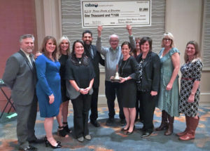 educators hold up a prop check after winning award