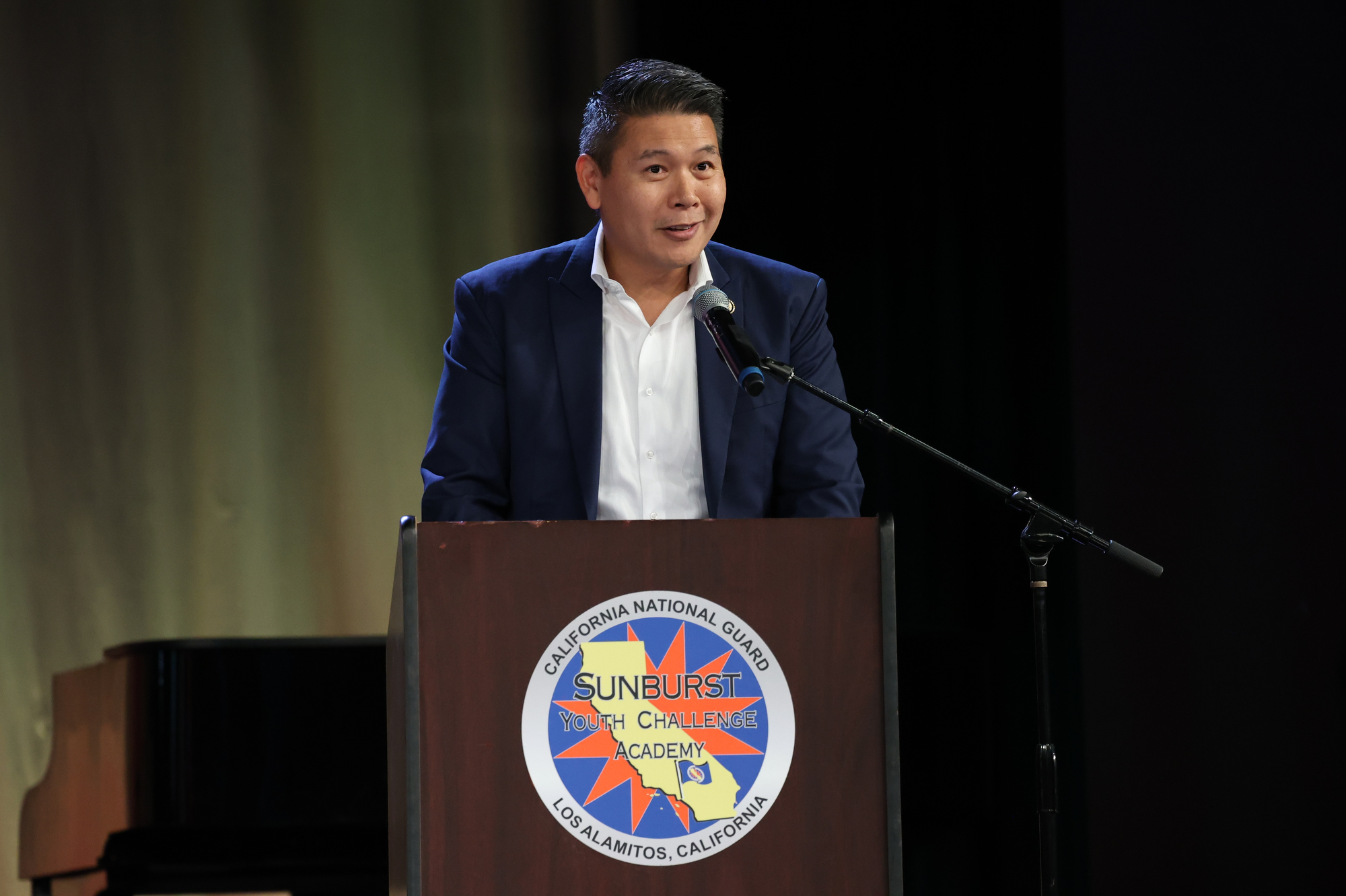Congressman Derek Tran speaks at a podium with the Sunburst Youth Challenge Academy logo during the Class 35 commencement ceremony.