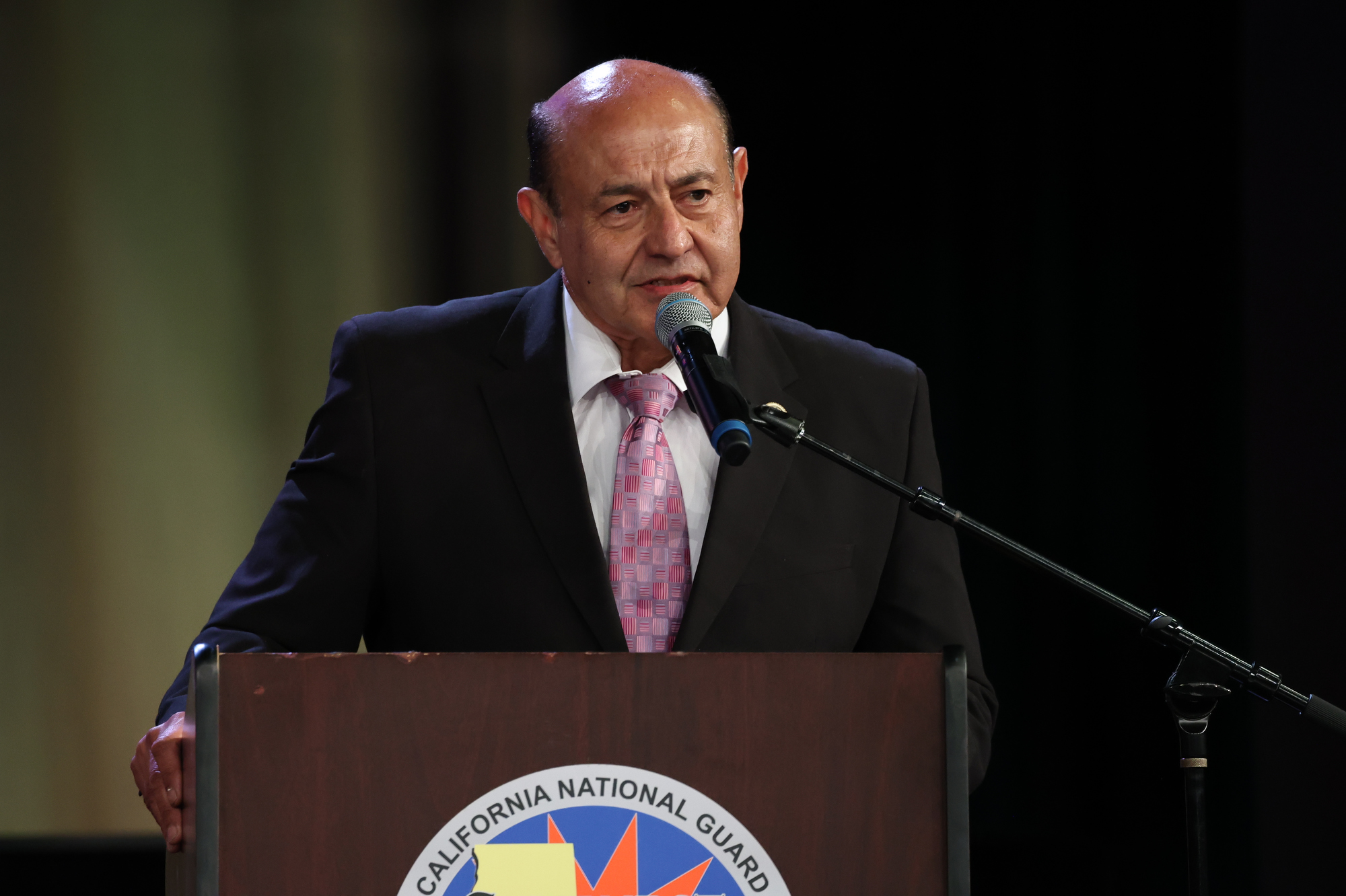 Congressman Lou Correa speaks at a podium bearing the California National Guard emblem during the Sunburst Youth Academy Class 35 commencement ceremony.