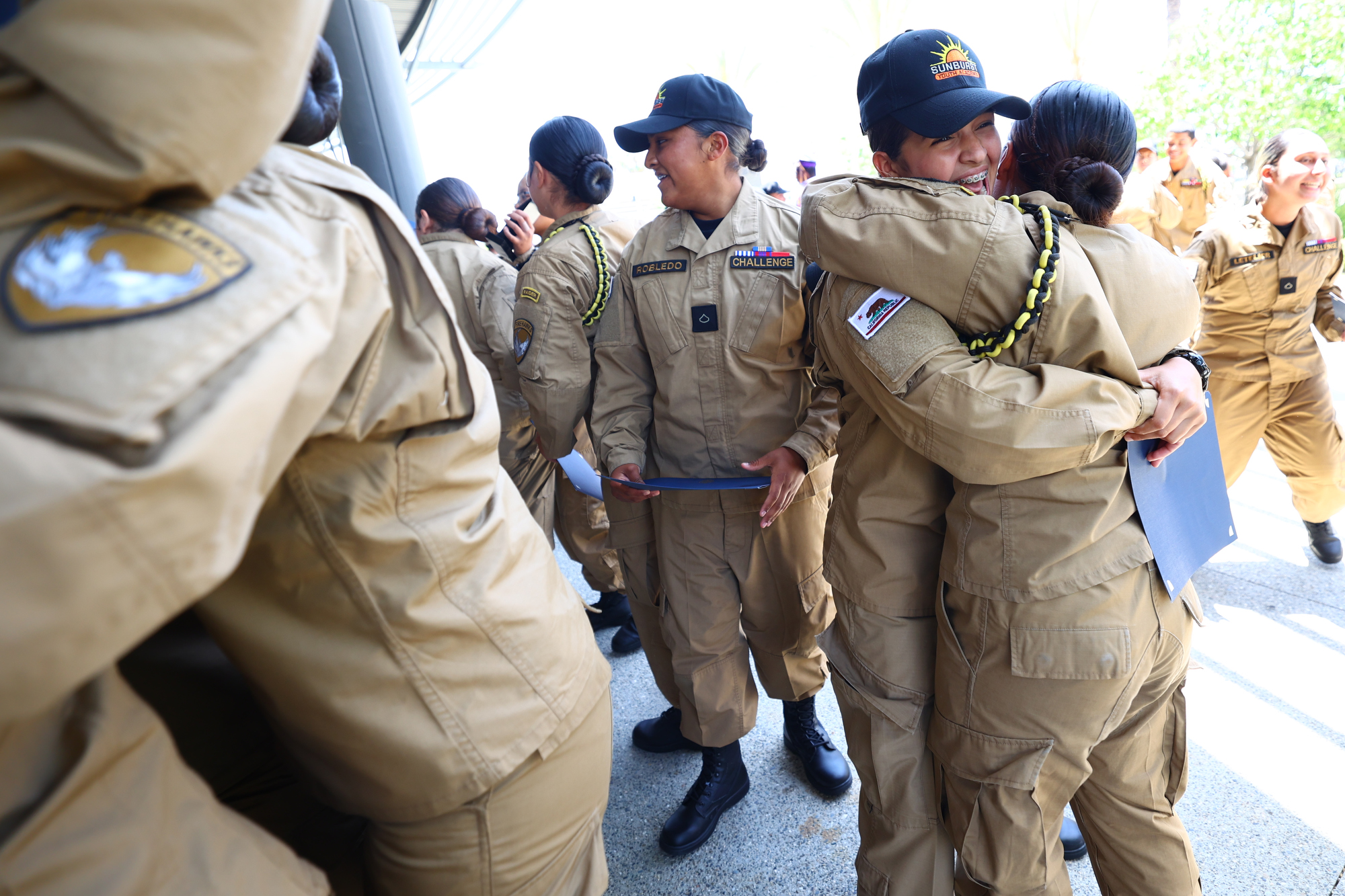 Sunburst Youth Academy cadets in uniform embrace and smile outside the venue following their graduation ceremony.