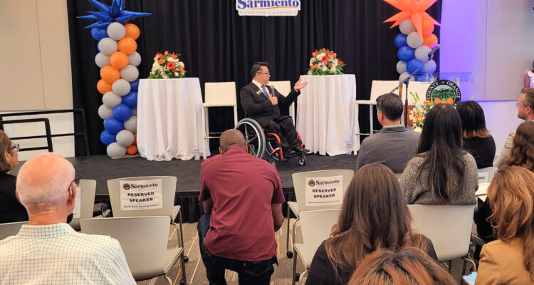 Dr. Stefan Bean addresses an audience from the stage at the Small-Scale Housing Summit in Santa Ana.