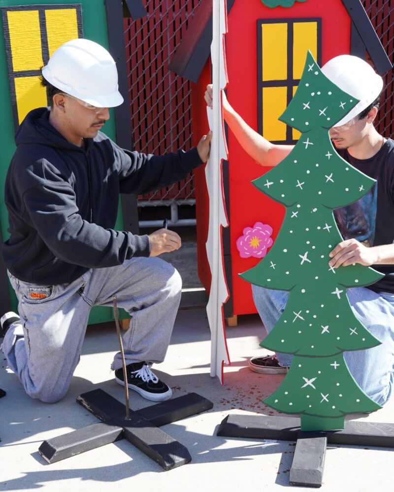 Estancia High School students secure wooden Christmas tree cutouts as they prepare finished pieces for the City of Costa Mesa’s Snoopy House display.