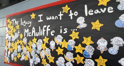 A student-created display at McAuliffe Middle School shows handwritten reflections on paper stars and astronaut cutouts under the message, “The legacy I want to leave at McAuliffe is …”