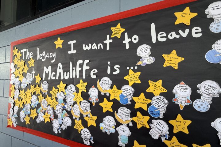 A student-created display at McAuliffe Middle School shows handwritten reflections on paper stars and astronaut cutouts under the message, “The legacy I want to leave at McAuliffe is …”