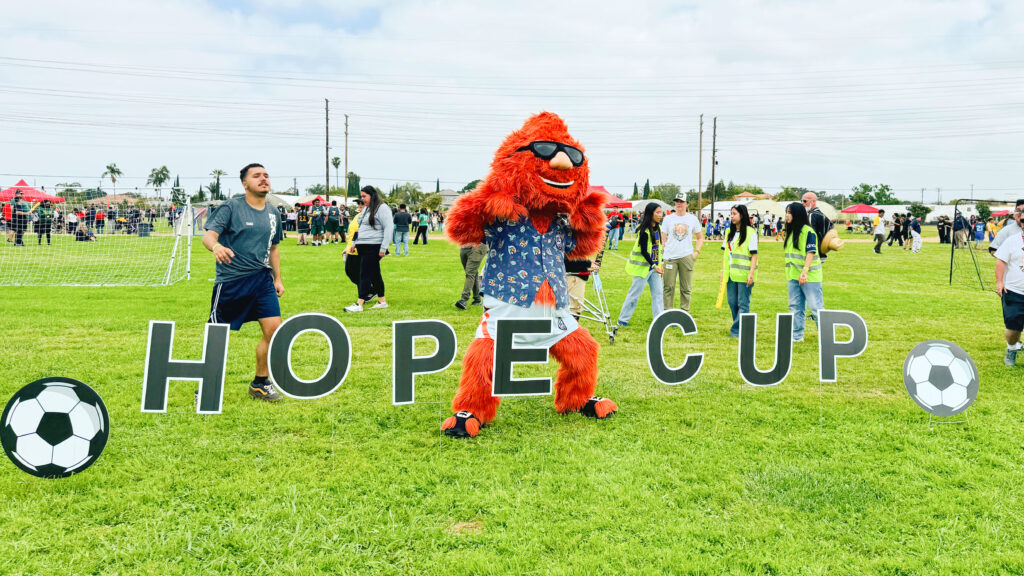 Mascot in front of Hope Cup sign