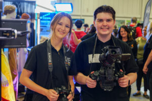 Two high school students holding professional camera equipment