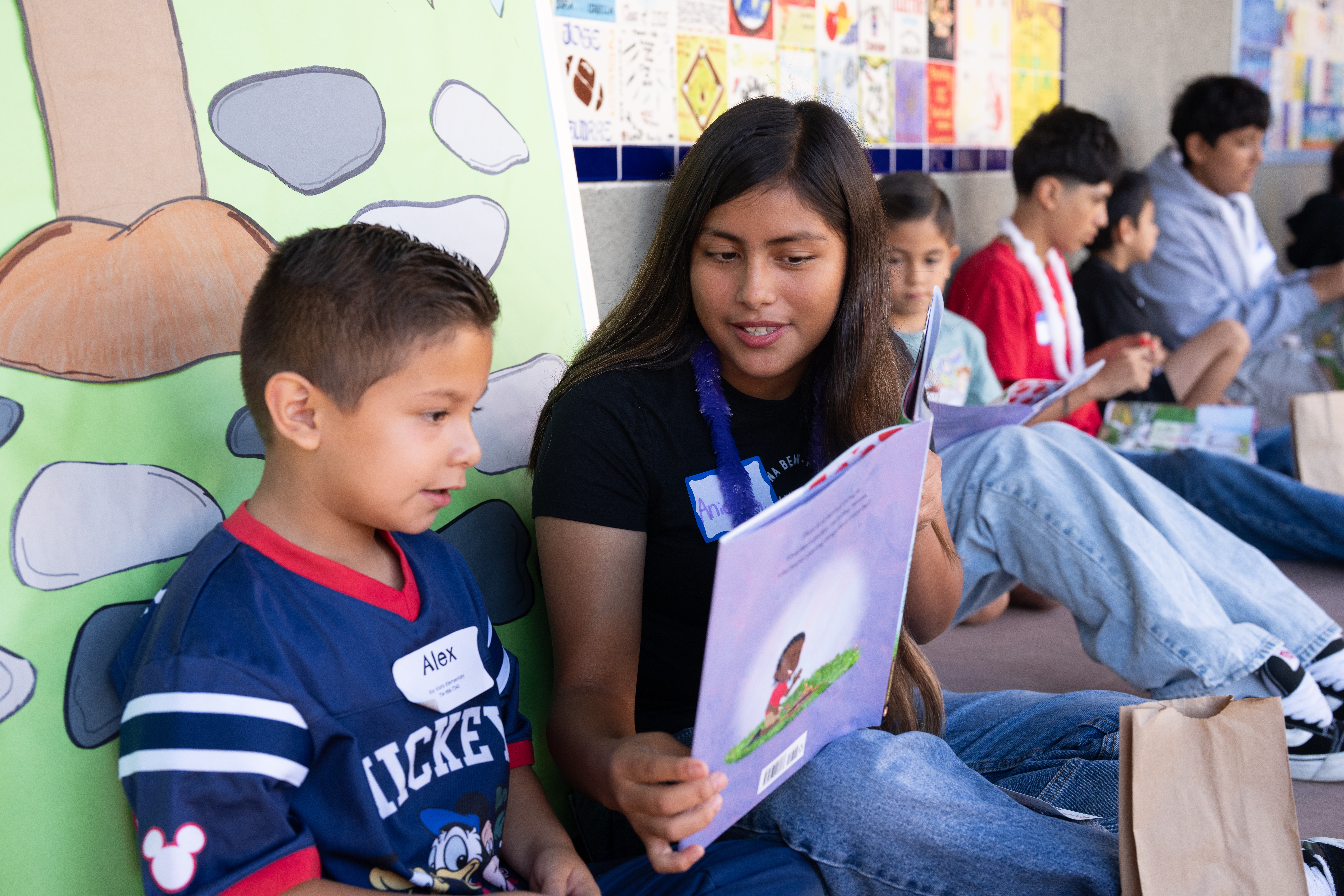 An older student reads to a new younger buddy named Alex.