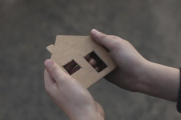 Child's hands with cardboard house