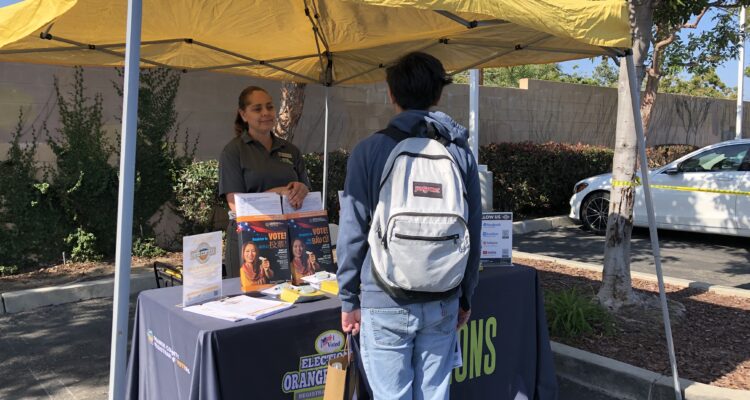 Orange County Registrar of Voters representative speaks to a student at a youth resource fair on June 22, 2023.