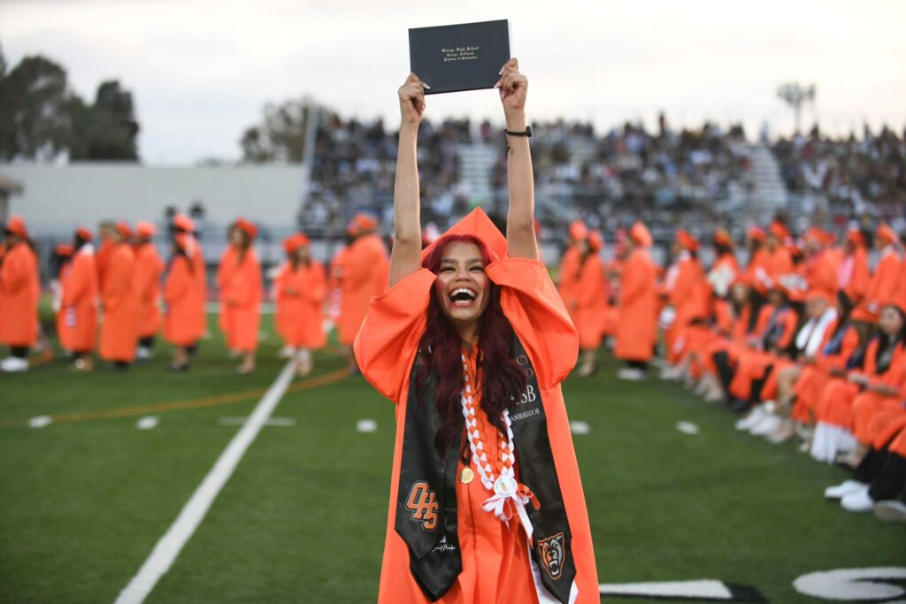 A 2024 Orange High School graduate holds up her diploma at graduation. (Orange Unified School District)