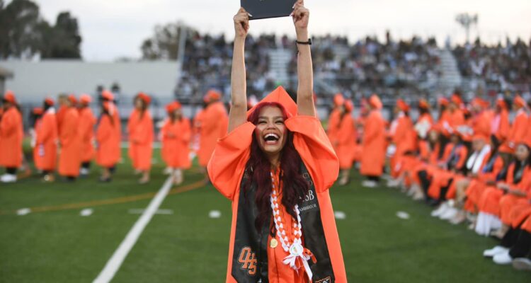 A 2024 Orange High School graduate holds up her diploma at graduation. (Orange Unified School District)