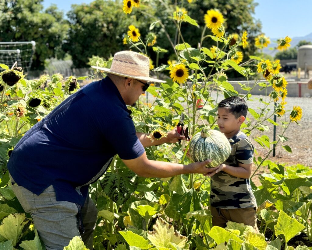 Moises Plascencia handing a pumkin to Julian.