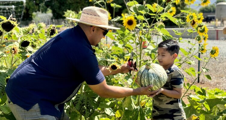 Moises Plascencia handing a pumkin to Julian.