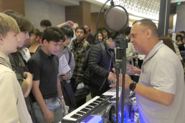 Students interact with an industry professional at a Future Leaders Conference exhibit, featuring a keyboard, microphone, and other tools for hands-on learning and career exploration.